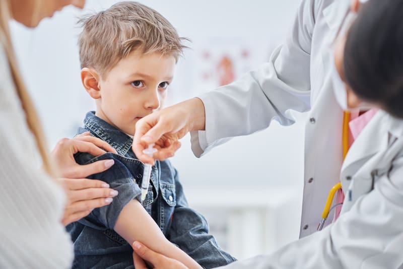 Little boy being vaccinated by pediatrician A little boy being vaccinated by a doctor as his mom stands next to him