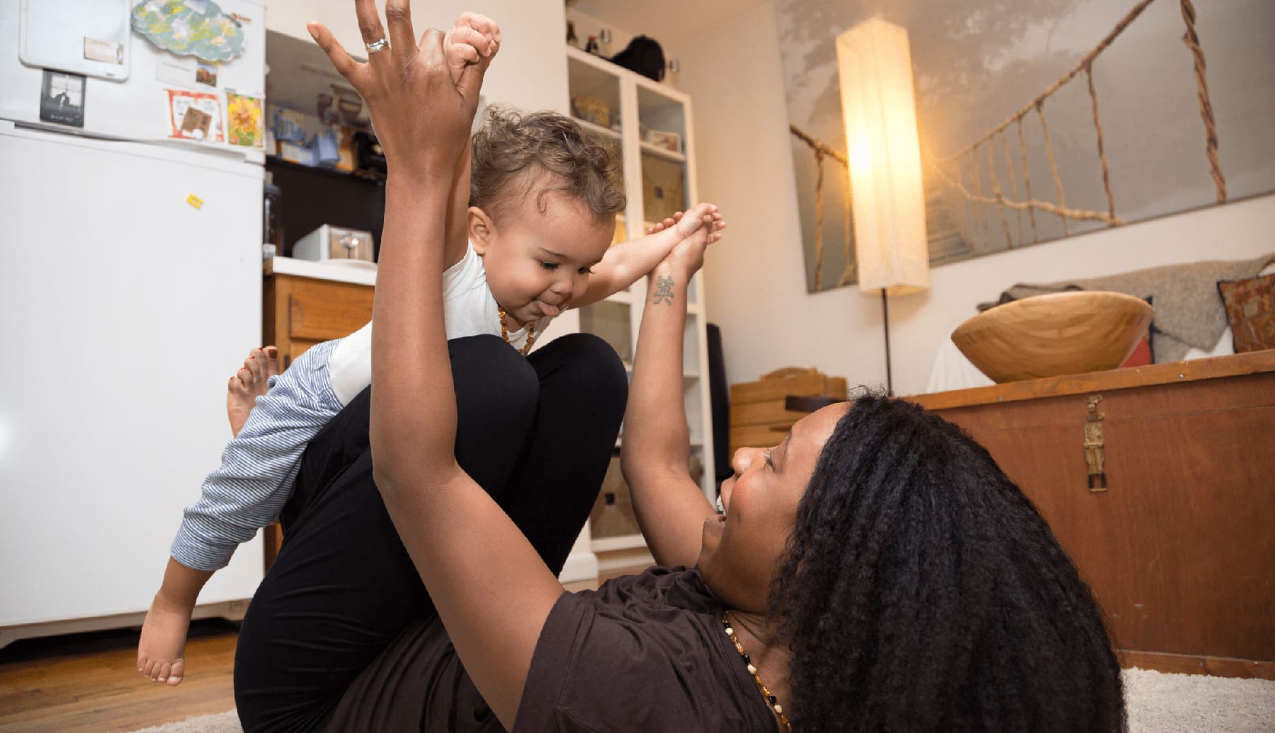 Mid adult woman lying on rug playing with toddler daughter as they improve their parent-child bond.