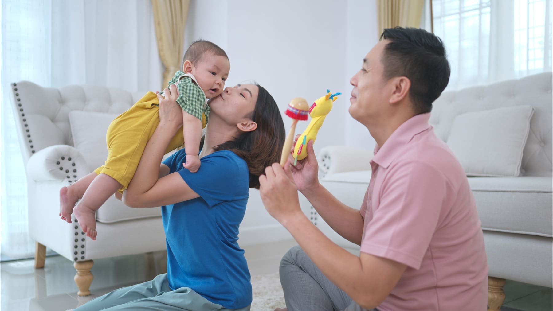 Parents and their little child play happily in the living room of the house